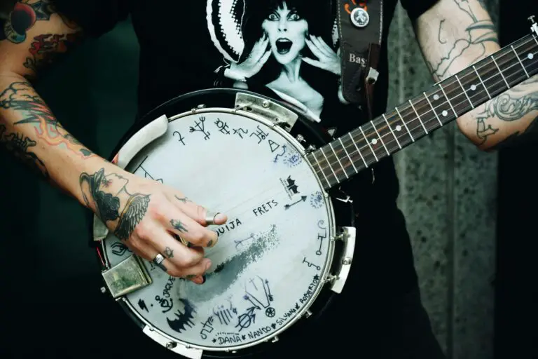 A tattooed man playing the banjo.